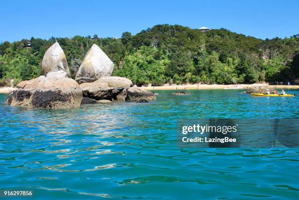 kayakers in hired kayak paddle around split apple rock, able tasman national park, tasman region, new zealand - kaiteriteri stock pictures, royalty-free photos & images