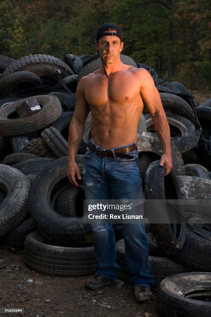 Bodybuilder standing in front of a pile of tires