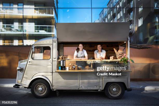 portrait of female owners in food truck parked on city street against building - restaurant ambulant photos et images de collection