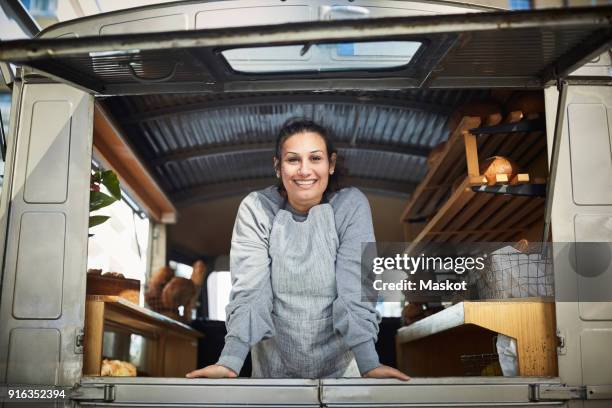 portrait of smiling mid adult owner standing in food truck - entrepreneur stockfoto's en -beelden