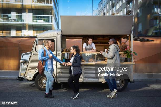 female owner in concession stand while customers having food and drink on street in city - foodtruck stock pictures, royalty-free photos & images