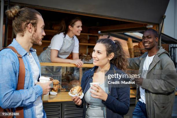 friends talking while having food and coffee by concession stand - food stall stock pictures, royalty-free photos & images