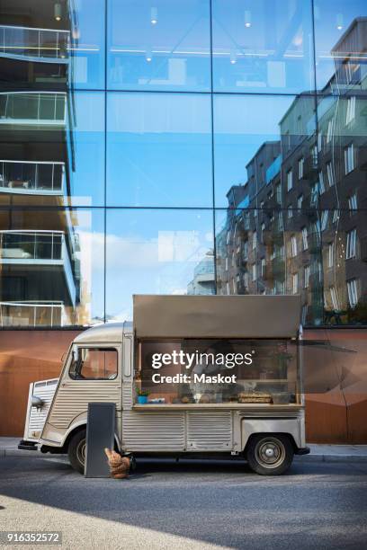 young male owner in food truck parked on city street against glass building - foodtruck stock pictures, royalty-free photos & images