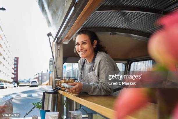 smiling mid adult female owner at food truck in city - furgone ambulante foto e immagini stock