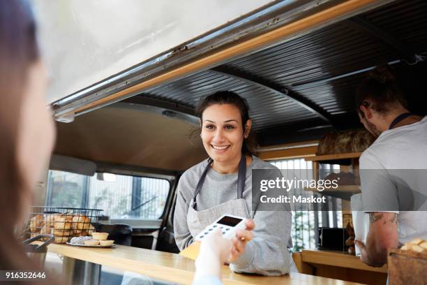 smiling female owner accepting credit card payment from customer at concession stand - food truck payments stock pictures, royalty-free photos & images