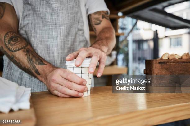 midsection of salesman packing disposable coffee cup in food truck - coffee to go becher stock-fotos und bilder