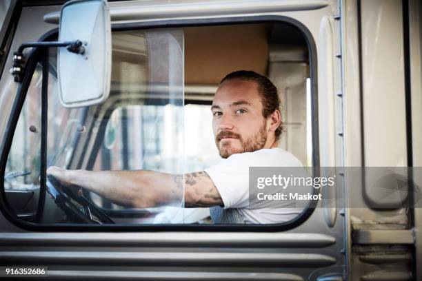 portrait of young man driving food truck in city - lkw fahrer stock-fotos und bilder