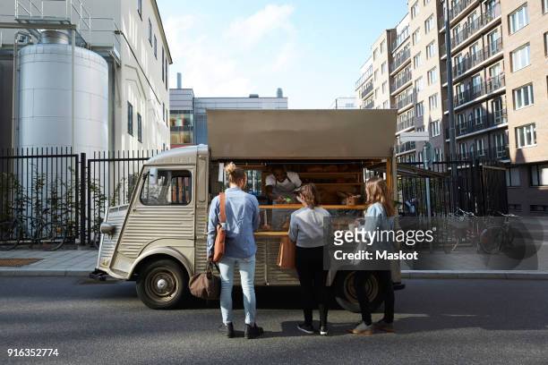 customers buying bread from salesman at food truck parked on city street - outdoor concession stand stock pictures, royalty-free photos & images