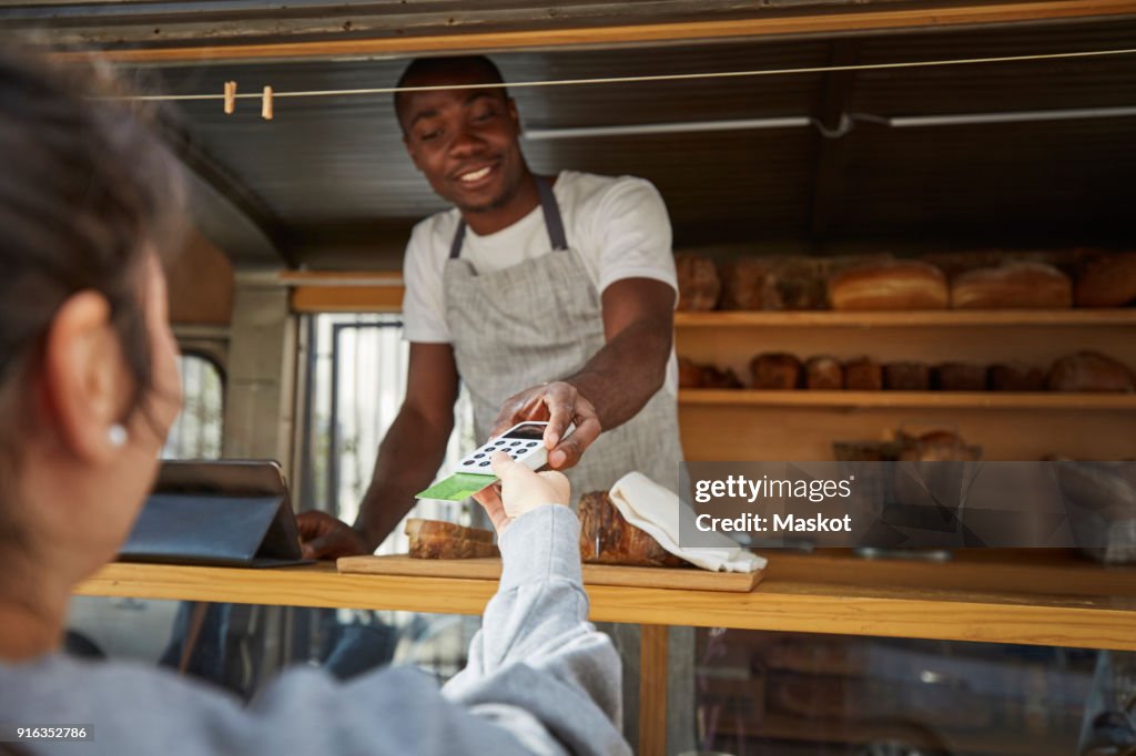 Woman with credit card paying salesman at food truck