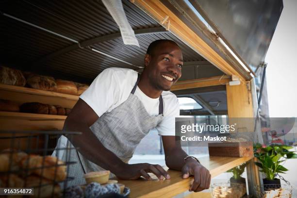 smiling salesman looking away while standing in food truck - food truck 個照片及圖片檔