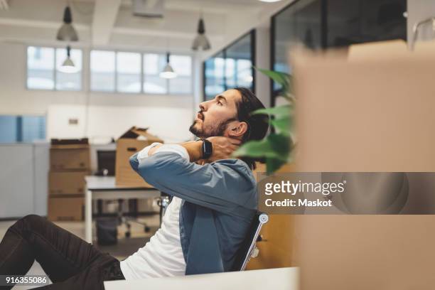 side view of young businessman having neck ache while sitting in new office - neckache stock-fotos und bilder