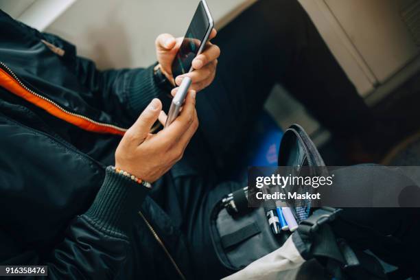 man checking blood sugar level with glaucometer while using mobile phone in train - glaucometer stockfoto's en -beelden