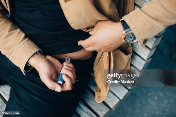 midsection of man injecting insulin while sitting on bench - insulin pen stock pictures, royalty-free photos & images