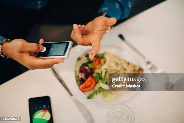 businessman checking blood sugar level with glaucometer while having food at table - glaucometer stockfoto's en -beelden