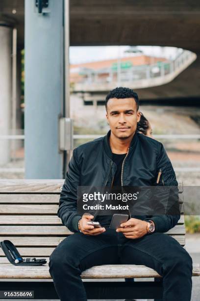 portrait of man holding glaucometer and smart phone while sitting on bench - glaucometer stockfoto's en -beelden