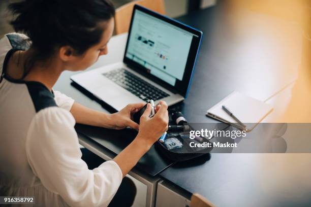 businesswoman checking blood sugar level with glaucometer by laptop at desk - glaucometer stock pictures, royalty-free photos & images