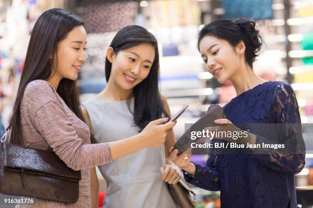 friends paying with smart phone in clothing store - woman coding stockfoto's en -beelden