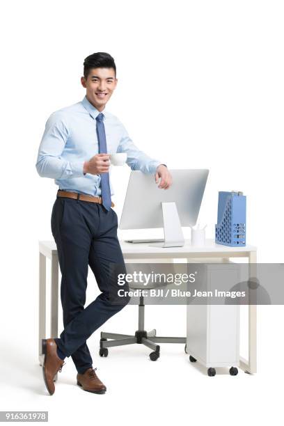 young businessman drinking coffee in office - man leaning chair standing side view stock pictures, royalty-free photos & images