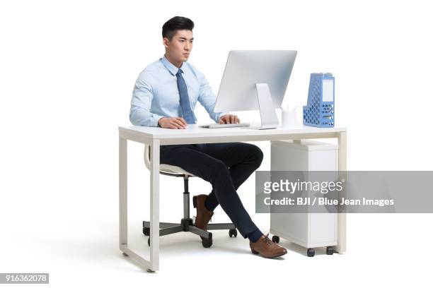 serious young businessman working in office - asian man sitting at desk ストックフォトと画像