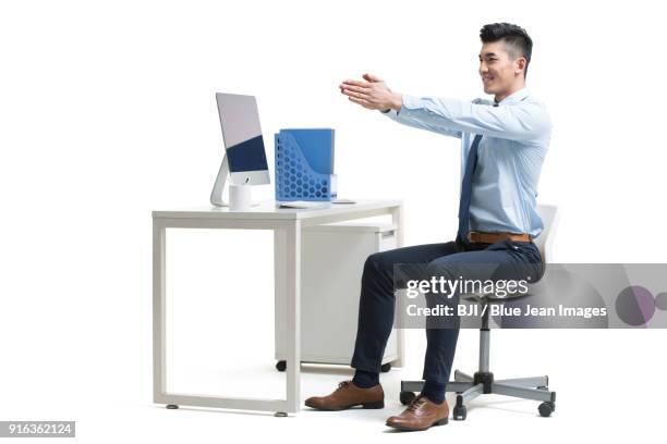 young businessman exercising in office - stretching while sitting on a chair stock pictures, royalty-free photos & images