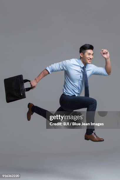 cheerful young businessman running with briefcase - legs spread stock-fotos und bilder