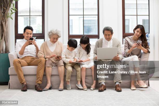 happy family using digital devices on sofa - autonomo smartphone tablet stock-fotos und bilder