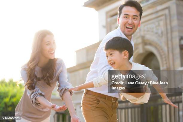 happy young family playing outside - dreiviertel vorderansicht stock-fotos und bilder