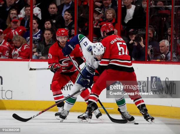 Trevor van Riemsdyk of the Carolina Hurricanes and Loui Eriksson of the Vancouver Canucks battle for the loose puck during an NHL game on February 9,...