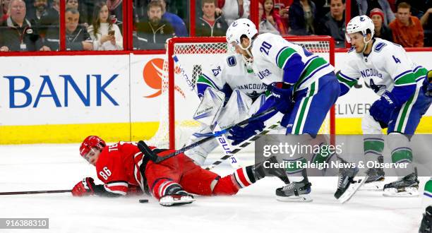 The Carolina Hurricanes' Teuvo Teravainen looks back at the puck after he is upended by the Vancouver Canucks' Brandon Sutter and Michael Del Zotto...