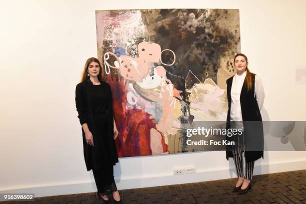 Hors Cadre Gallery cofounders Oceane Sailly and Manon Sailly pose with a work of russian painter Victoria Kosheleva during the "Hors Cadre"...