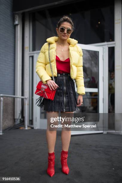 Guest is seen on the street attending the Bibhu Mohapatra show during New York Fashion Week wearing a yellow down coat with black fringe leather...