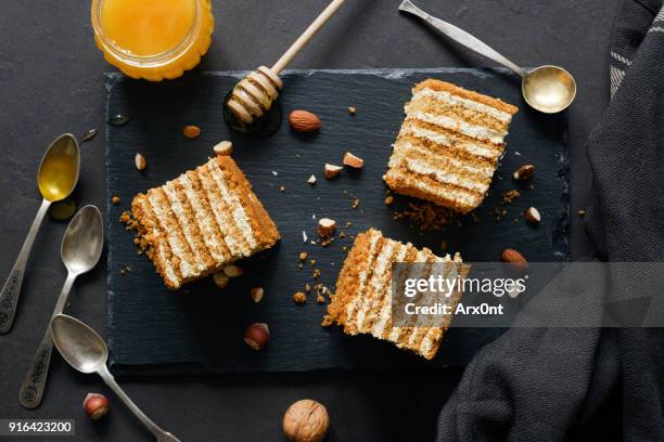 layered honey cake medovik on dark background - cremetorte stock-fotos und bilder