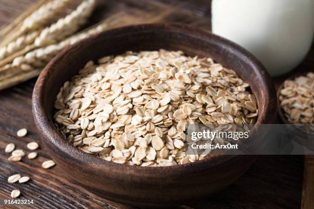 rolled oats in wooden bowl on old wooden table - oat stock pictures, royalty-free photos & images