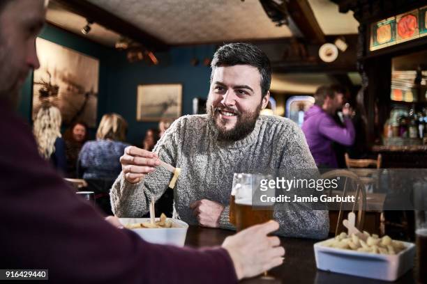 british bearded male in his early 30's eating chips in traditional pub - british culture stock pictures, royalty-free photos & images