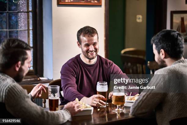 three friends sat in a traditional british pub enjoying each others company - mates pub stock-fotos und bilder