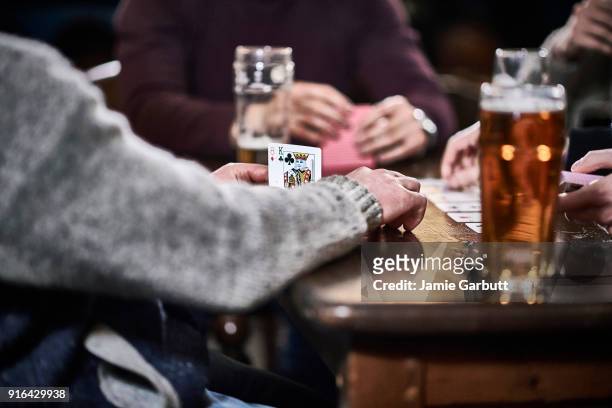close up shot of the hands of a group of men playing cards - pub mates stock-fotos und bilder