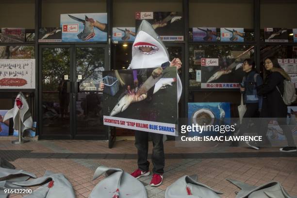 Shark fin activist holds a placard outside a Maxim's restaurant, the largest Chinese restaurant group in Hong Kong, during a rally by environmental...