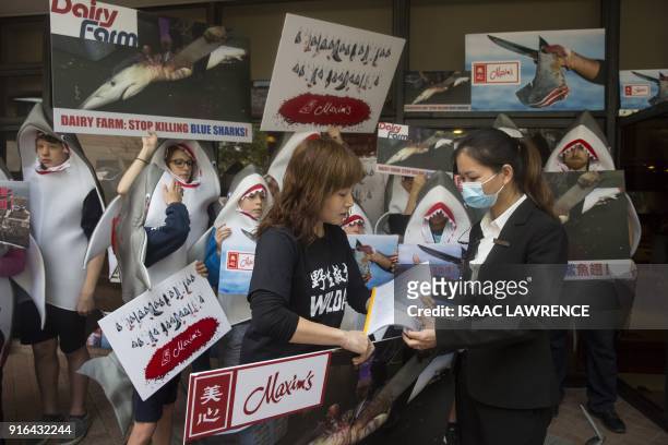 Member of conservation NGO WildAid hands a petition to a Maxim's representative , calling for an end to the selling of shark fin, in front of...