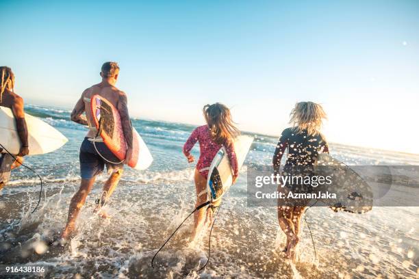 friends running into the ocean with surfboards - gold coast surfing stock pictures, royalty-free photos & images