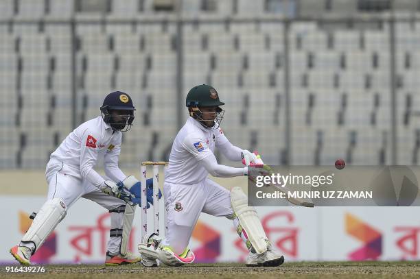 Bangladesh cricketer Mushfiqur Rahim plays a shot as the Sri Lanka wicketkeeper Niroshan Dickwella looks on during the third day of the second...