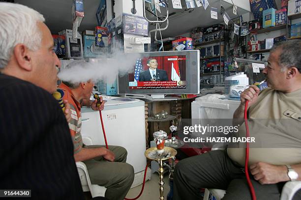 Palestinians smoke waterpipes as they listen to US President Barack Obama's speech at Cairo University, at a shop in the West Bank city of Hebron on...