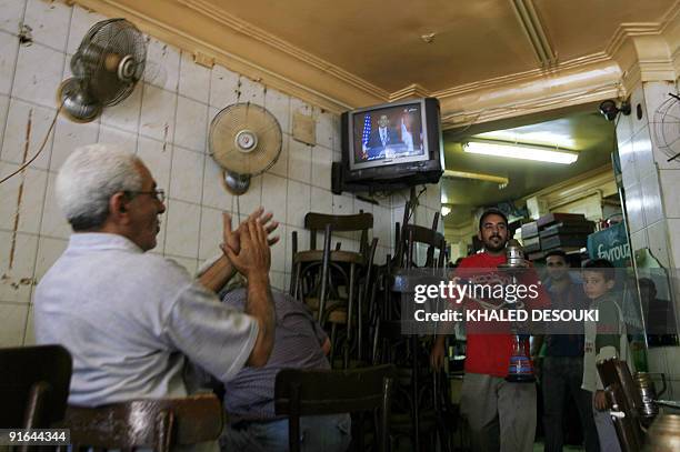 An Egyptian man applauds as he listens to US President Barack Obama's speech at Cairo University, at a coffee shop in Cairo on June 4, 2009....