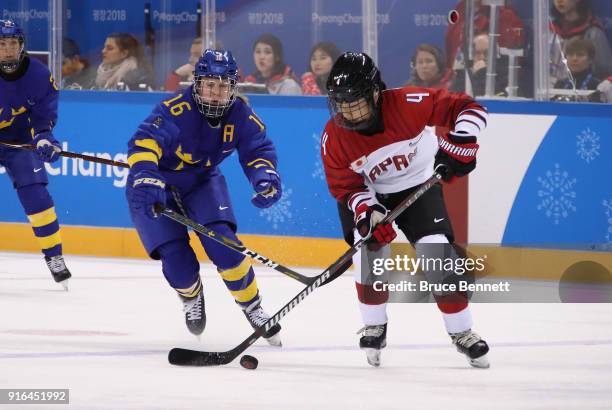 Pernilla Winberg of Sweden and Ayaka Toko of Japan battle for the puck in the first period during the Women's Ice Hockey Preliminary Round - Group B...