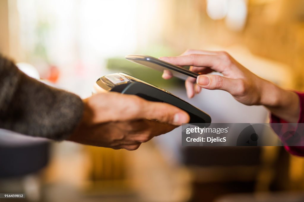 Kontaktloses Bezahlen mit einem Hand-Smartphone hautnah.