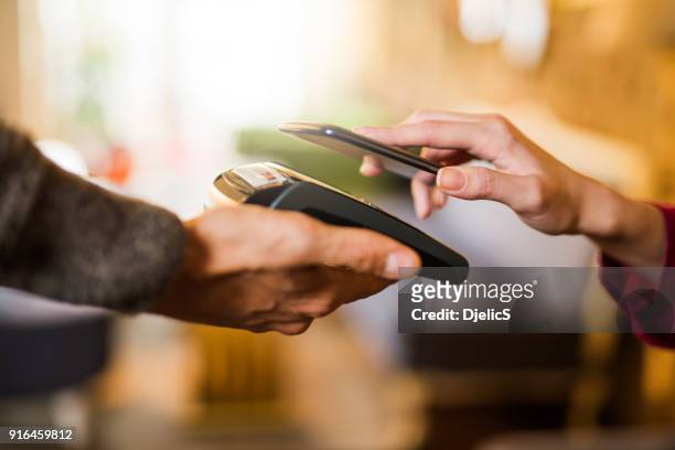 kontaktloses bezahlen mit einem hand-smartphone hautnah. - paying stock-fotos und bilder