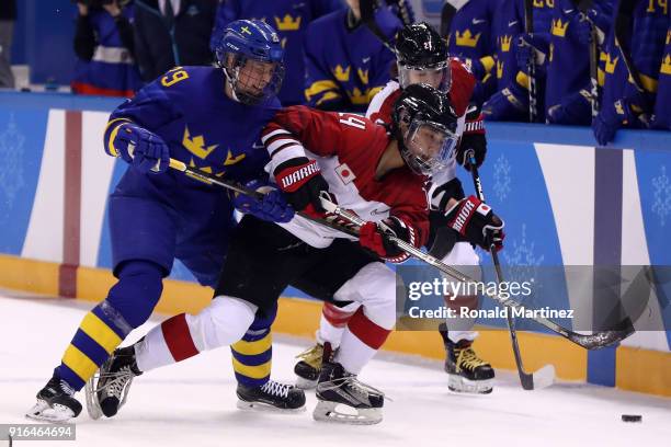 Haruka Toko of Japan competes for the puck with Olivia Carlsson of Sweden during the Women's Ice Hockey Preliminary Round - Group B game on day one...