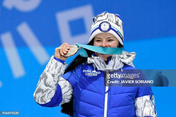 Finland's Krista Parmakoski celebrateS on the podium during the medal ceremony after taking third place in the women's 7.5km + 7.5km cross-country...
