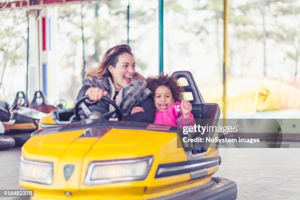 single mother with children, driving bumper cars in amusement park - joy ride stock pictures, royalty-free photos & images