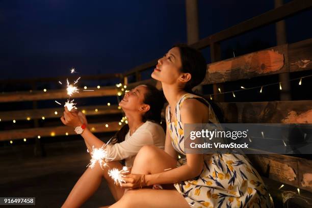 two young women set off fireworks - chinese friends stock pictures, royalty-free photos & images