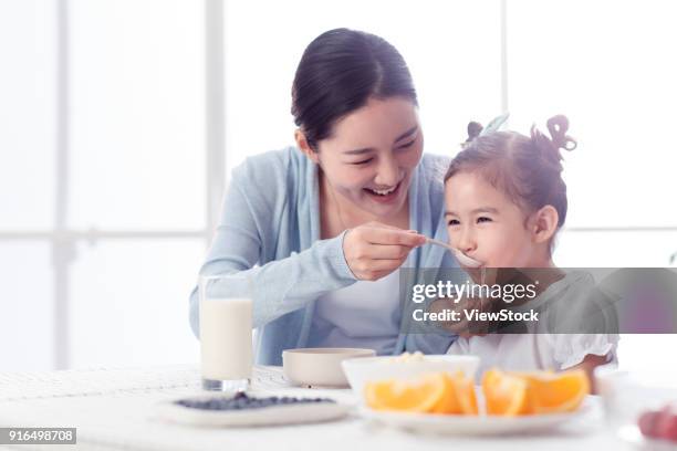 mother is feeding the girl - asian spoon feeding happy stock pictures, royalty-free photos & images